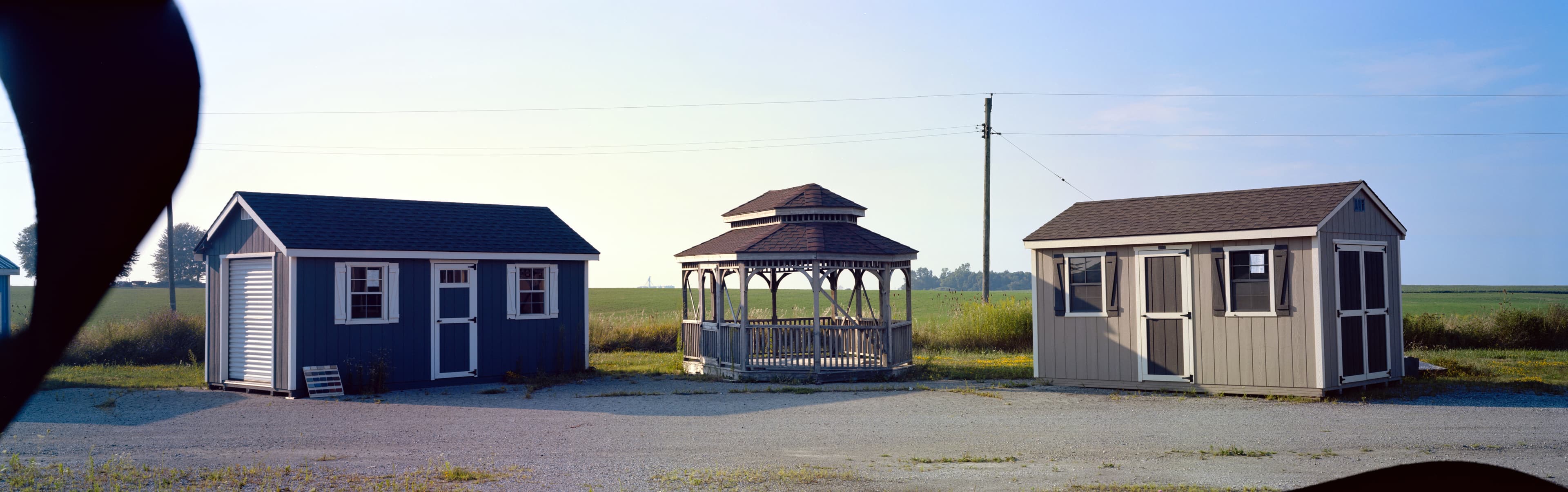 Two sheds symetrically surrounding a dainty gazebo in a field