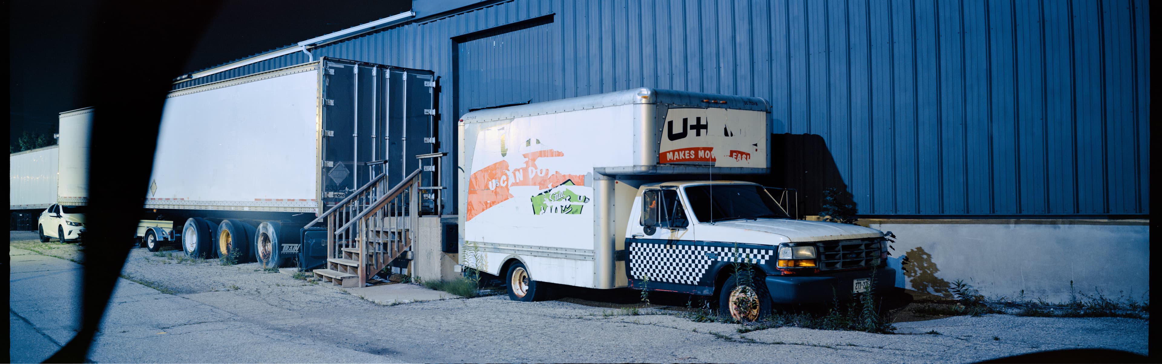 An abandoned box truck against a dark building entrance